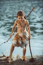 Angry caveman, manly boy with ancient primitive weapon hunting outdoors. Ancient prehistoric warrior. Heroic movie look Royalty Free Stock Photo