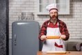 Angry chef bakers man raising rolling pin threateningly in white kitchen. Royalty Free Stock Photo