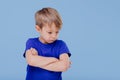 Angry child llittle boy dressed in blue T-shirt, on blue background