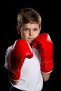 An angry, confident boxer with red gloves. Self defending position, boy portrait on the black background