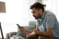 Angry confused man holding discharged phone annoyed by spam message Royalty Free Stock Photo