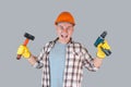 An angry construction worker in hardhat screams with a tool in his hands holding a screwdriver and a hammer Royalty Free Stock Photo
