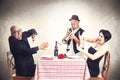 Angry couple disturbed by a trumpet musician while having dinner Royalty Free Stock Photo