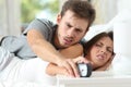 Angry couple turning off the alarm clock Royalty Free Stock Photo