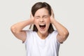 Angry crazy teen girl covering ears screaming isolated on background