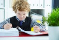 Angry curly Caucasian boy like businessman doing paperwork in office.