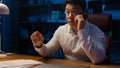 Angry disappointed Asian businessman mad aggressive talking mobile phone at night evening office dissatisfied with Royalty Free Stock Photo