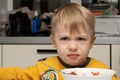Angry and displeased little blond boy 3 years old is eating soup and bread in the kitchen at the table and close-up Royalty Free Stock Photo