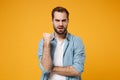 Angry dissatisfied young bearded man in casual blue shirt posing isolated on yellow orange background, studio portrait Royalty Free Stock Photo