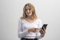 Angry or dissatisfied young woman staring at camera and showing at mobile phone in disbelief and annoy, white t-shirt and grey