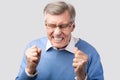 Angry Elderly Man Clenching Fists Posing On Gray Background, Studio