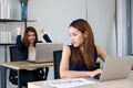 Angry envious Asian business woman looking successful competitor colleague in office. Royalty Free Stock Photo