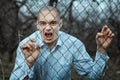 Angry and fearful man grinning over the fence mesh. Royalty Free Stock Photo