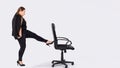Angry female boss firing employee. Dismissed frustrated business woman pushing office chair with foot. Business concept
