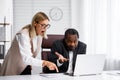 Angry female boss scolding African American office worker. A demanding manager-leader is annoyed by laziness and