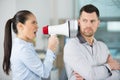 angry female boss shouting through megaphone at oblivious male employee Royalty Free Stock Photo