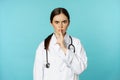 Angry female doctor, healthcare medical worker shushing with disapproval, taboo quiet gesture, silence someone, standing
