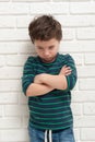 Angry frowning boy on brick wall background.