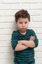 Angry frowning boy on brick wall background.