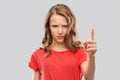 Angry frowning teenage girl pointing finger up