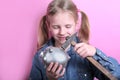 Angry funny young girl with silver piggy bank  and hammer on pink background. save money concept. Royalty Free Stock Photo