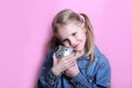 Angry funny young girl with silver piggy bank on pink background. save money concept. Royalty Free Stock Photo