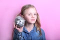 Angry funny young girl with silver piggy bank on pink background. save money concept. Royalty Free Stock Photo