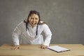 Angry furious female doctor shouting at camera standing behind desk studio shot