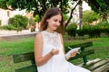 An angry girl is sitting on the bench in the park holding crumpled paper, a pen and a notebook Royalty Free Stock Photo