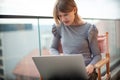 Angry girl sitting chair using laptop while sitting on balcony Royalty Free Stock Photo