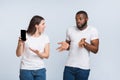 Angry girlfriend asking explanation from her unfaithful boyfriend, demonstrating his smartphone