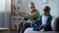 Angry grandfather scolding boy for playing video game on tablet, generation gap Royalty Free Stock Photo