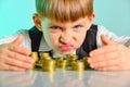 Angry and greedy child holds their money coins. The concept of greed, greed and vice from childhood