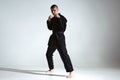 Angry guy trainer in black kimono fighter posing in karate stance on studio background with copy space Royalty Free Stock Photo