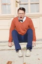 Angry handsome man with glasses and sweater sitting on steps in Royalty Free Stock Photo