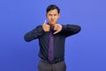 Angry handsome young businessman showing thumbs up and down on purple background