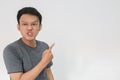 Angry and hate face of young Asian man in gray t-shirt with hand point on empty space Royalty Free Stock Photo