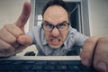 Angry hayter writes negative comments on the social network. Negative emotions of businessman employee in front of a computer. Royalty Free Stock Photo