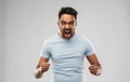 Angry indian man screaming over grey background
