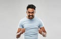 Angry indian man screaming over grey background