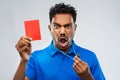 Angry indian referee with whistle showing red card