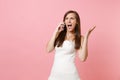 Angry Irritated bride woman in white wedding dress spreading hands, talking on mobile phone, screaming and swearing