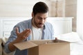 Angry irritated man unboxing parcel, wrong or broken order Royalty Free Stock Photo