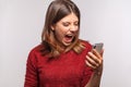 Angry irritated woman keeping mouth open roaring wild, shouting while looking at cell phone screen Royalty Free Stock Photo