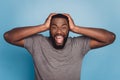 Angry irritated young african man screaming looking camera isolated on blue color background Royalty Free Stock Photo