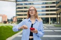 Angry irritated young business woman holding mobile phone and looks at his watch at the blurry business center building Royalty Free Stock Photo