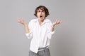 Angry irritated young business woman in white shirt posing isolated on grey wall background, studio portrait