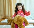 Angry little girl beating her teddy bear - domestic abuse concept. Girl 4-5 year old punishes toy bear