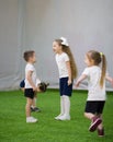 An angry little girl with long hair is shouting on a boy on the football field
