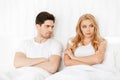 Angry loving couple lies in bed indoors at home quarrel.